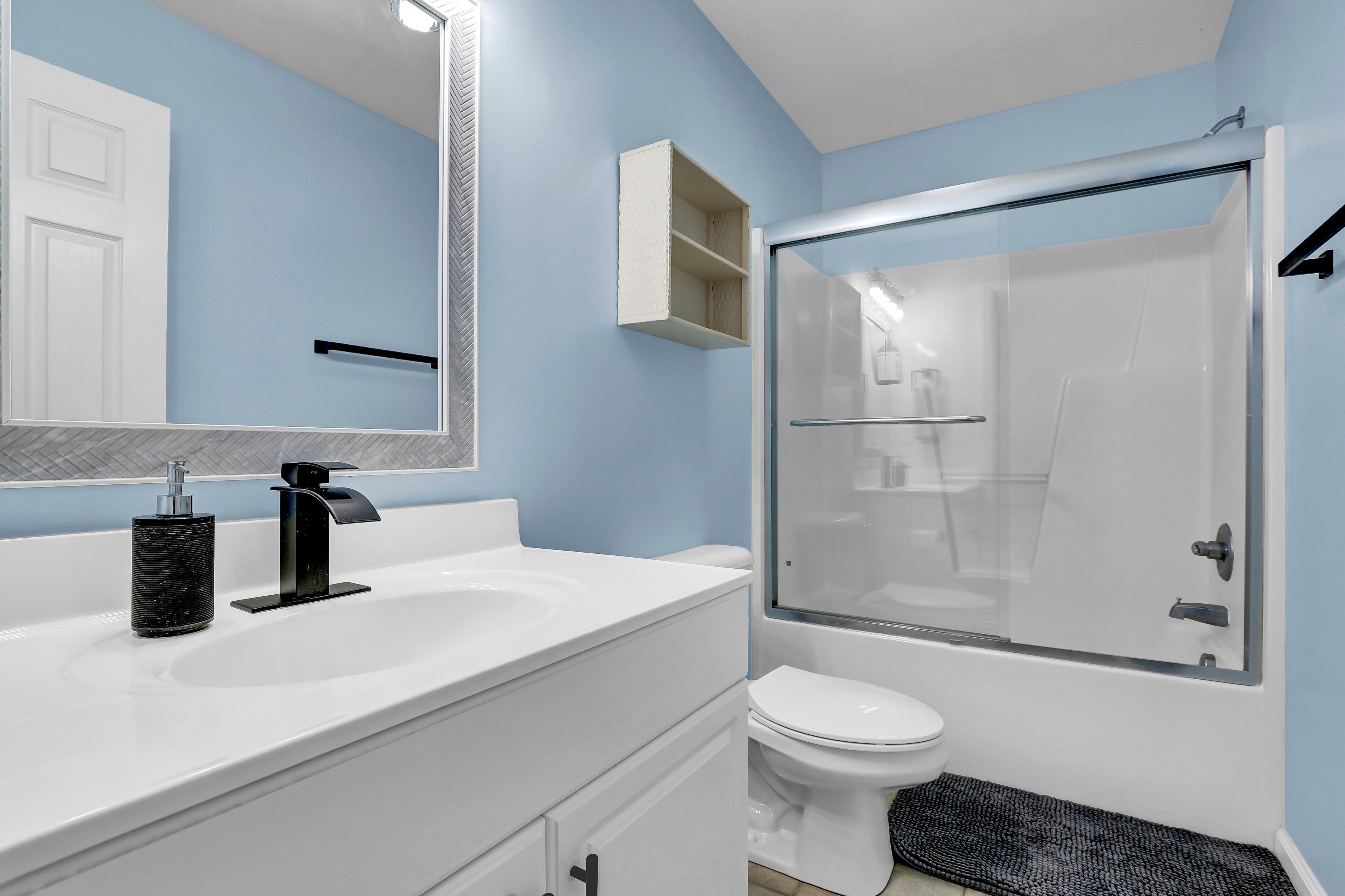 A bathroom with a white sink, a mirror, a toilet, and a glass-enclosed shower.