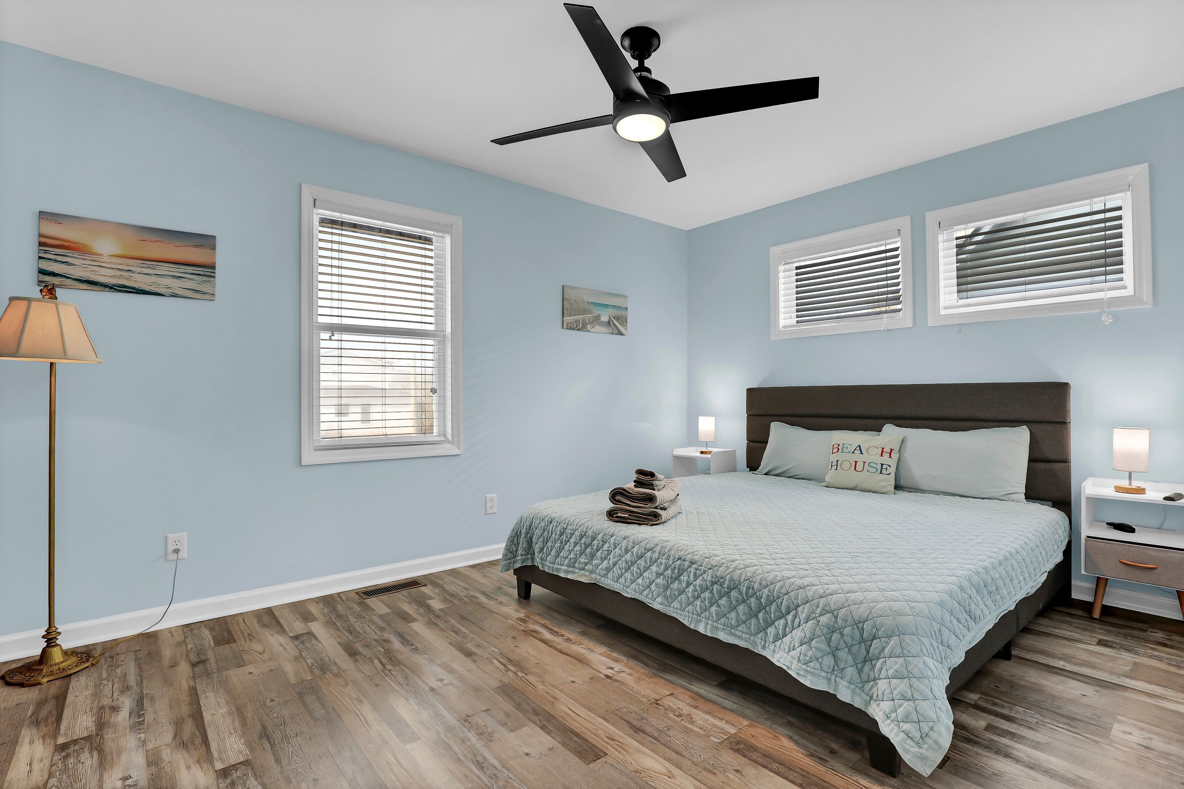 Une chambre à coucher avec un lit, un ventilateur de plafond et deux tables de chevet avec des lampes.