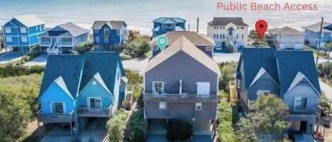 A residential area with houses, a road, and a beach in the background.