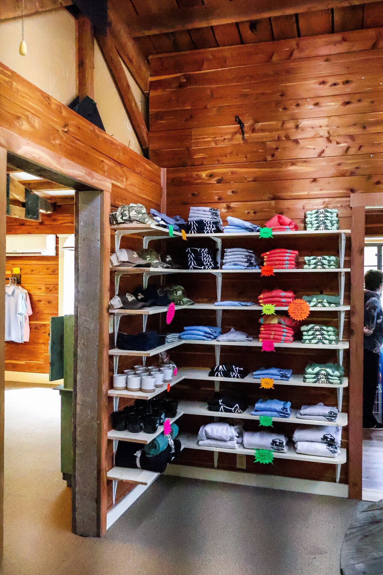 Un intérieur en bois avec un portant à vêtements où sont présentés divers vêtements pliés.