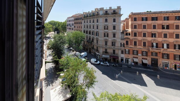 Una vista de carrer amb edificis, cotxes aparcats i arbres.