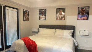 A bedroom with a bed, a red throw blanket, and three framed baseball player photos on the wall. - King Suite | 1mi to The Battery + Mins to Midtown! (Atlanta)