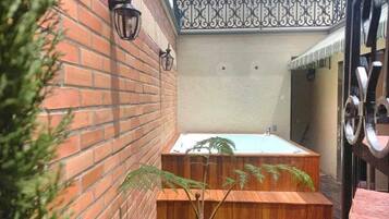 A brick wall with a wooden bench and a potted plant.