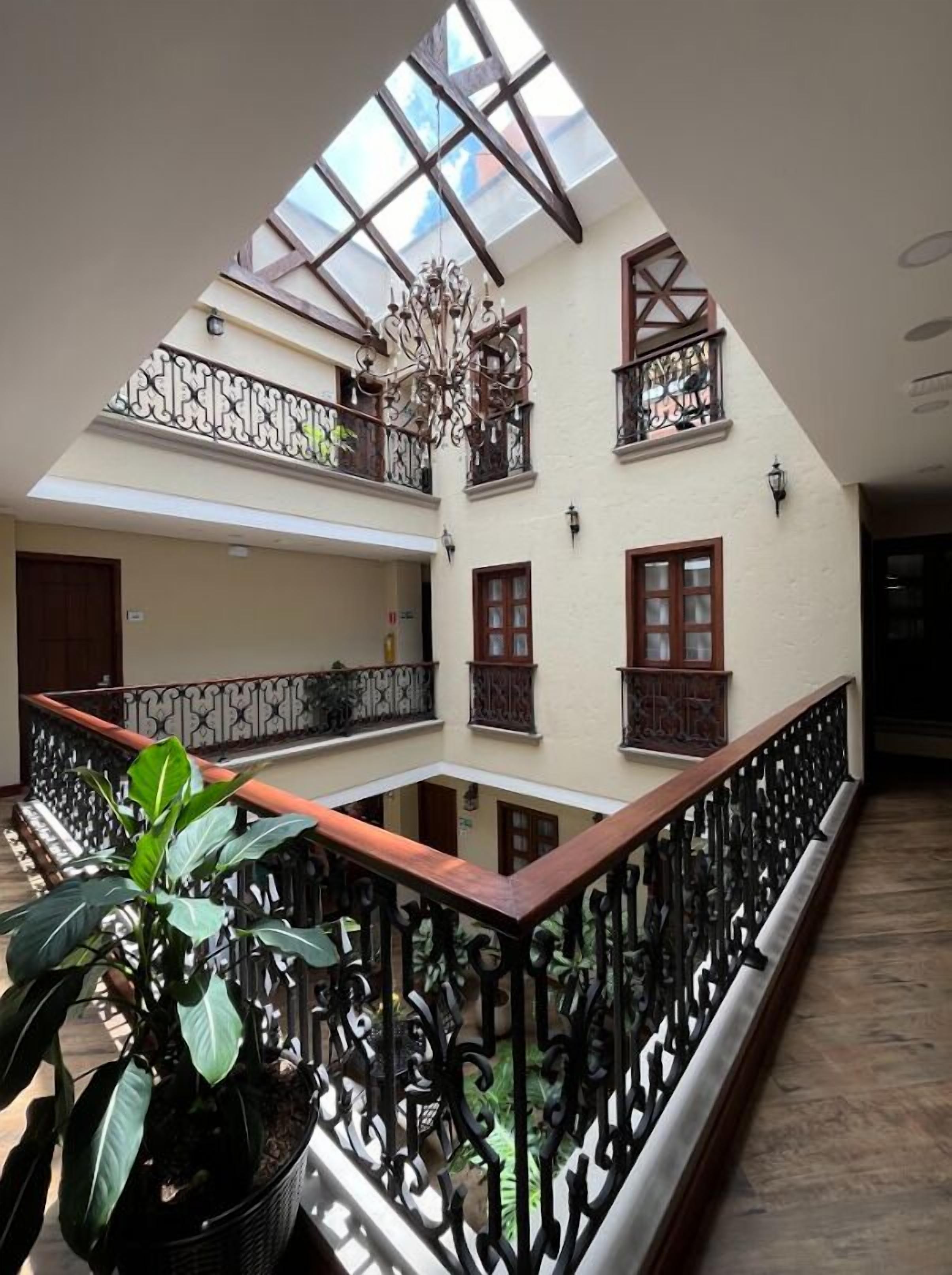 Een meerlaags atrium met een open centrale ruimte, houten balustrades en een kroonluchter.