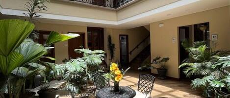 A multi-level atrium with a central seating area, surrounded by potted plants and featuring a staircase.