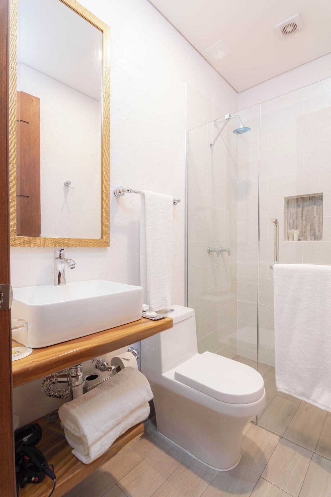 A modern bathroom with a white sink, toilet, and glass shower enclosure.