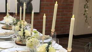 Une table dressée avec de l’argenterie, des verres et des bougies, décorée de fleurs blanches et de verdure.