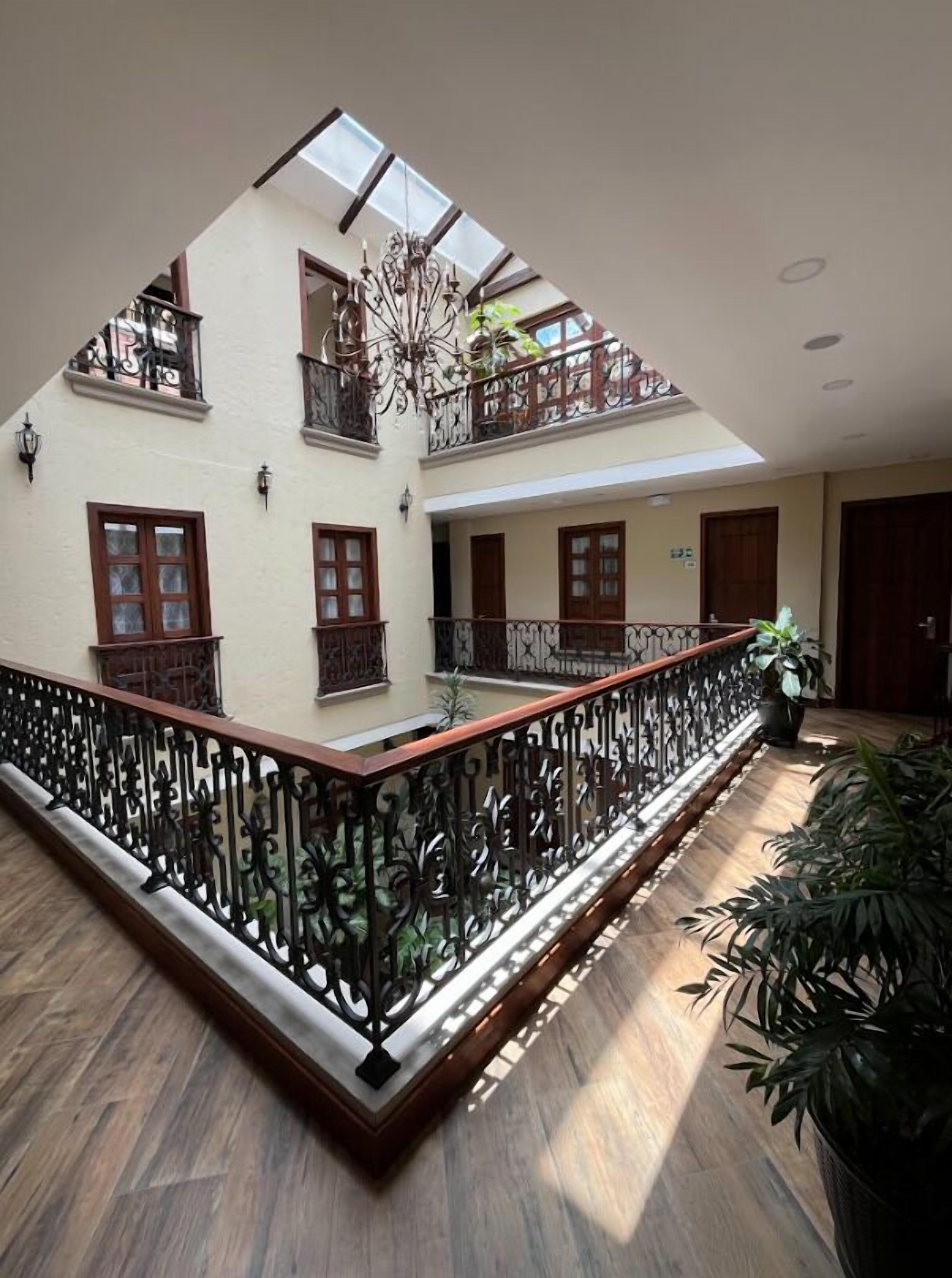 A multi-level interior with a central open space, wooden flooring, and a decorative railing.