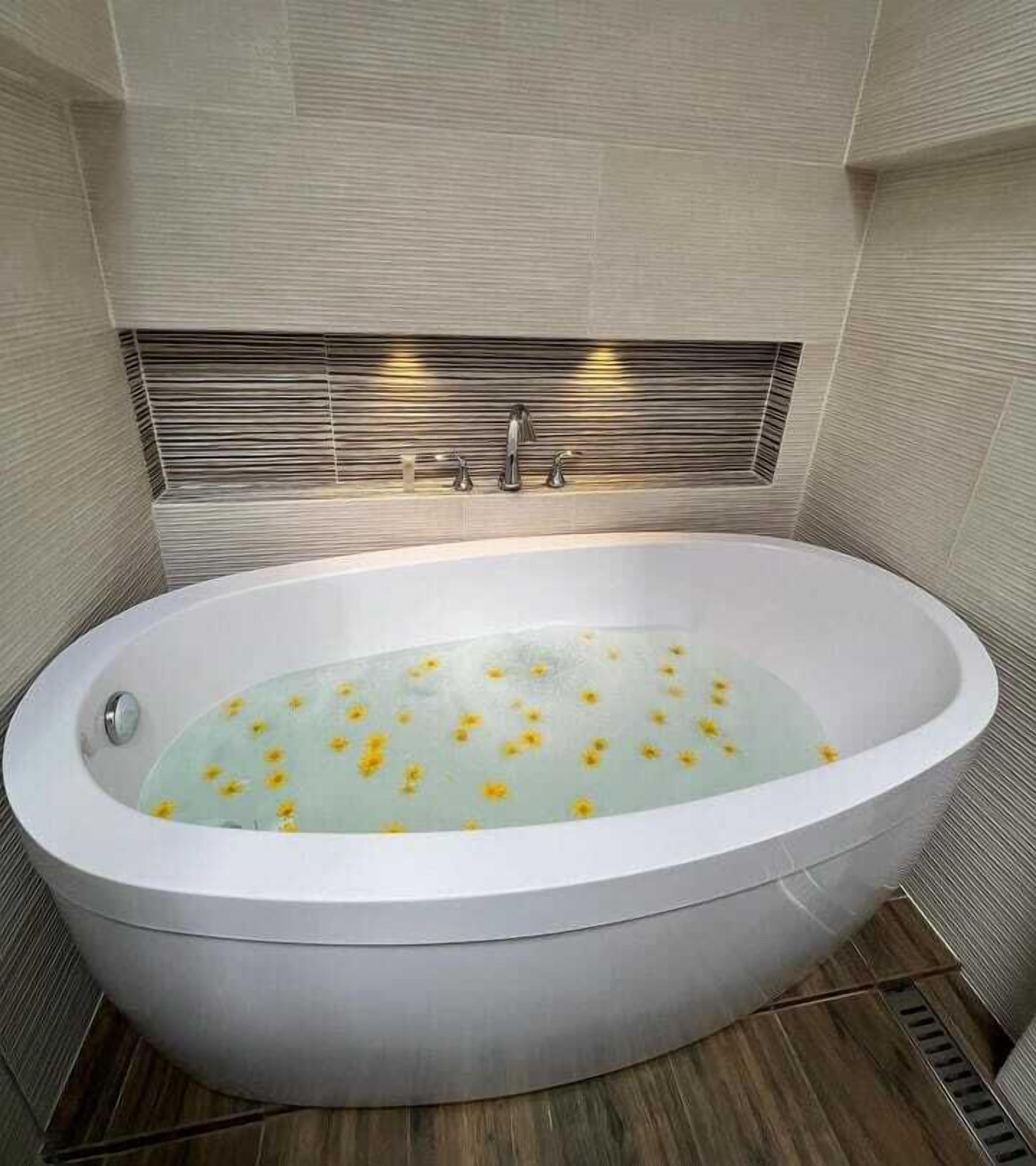 Un baño moderno con una bañera independiente, suelo de madera y pared de azulejos con un diseño horizontal.