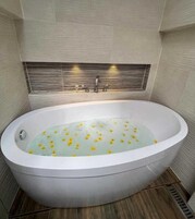 Un baño moderno con una bañera independiente, suelo de madera y pared de azulejos con un diseño horizontal.
