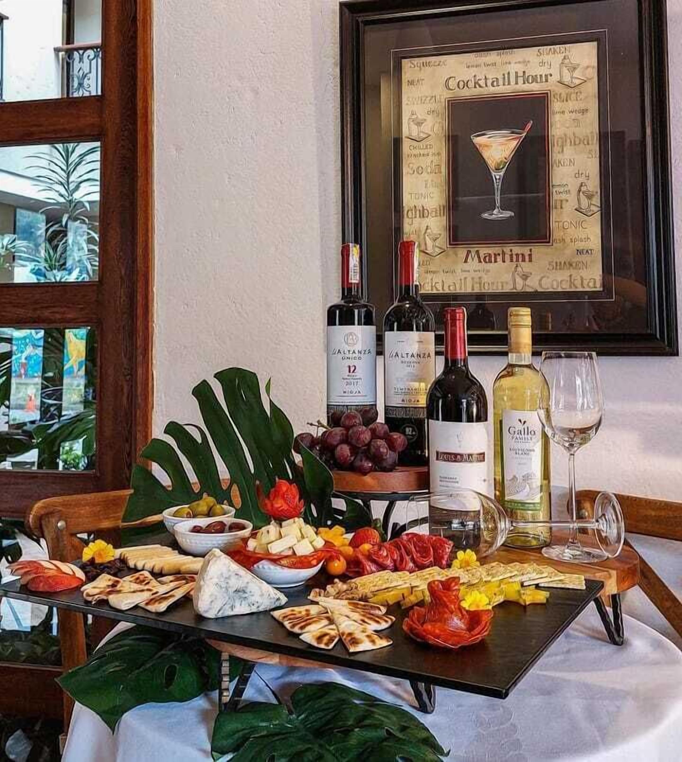A table set with various food items, wine bottles, and a framed menu on the wall.