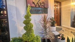L’entrée d’un hôtel, avec une enseigne indiquant « Hôtel de charme » et une variété de plantes en pot.