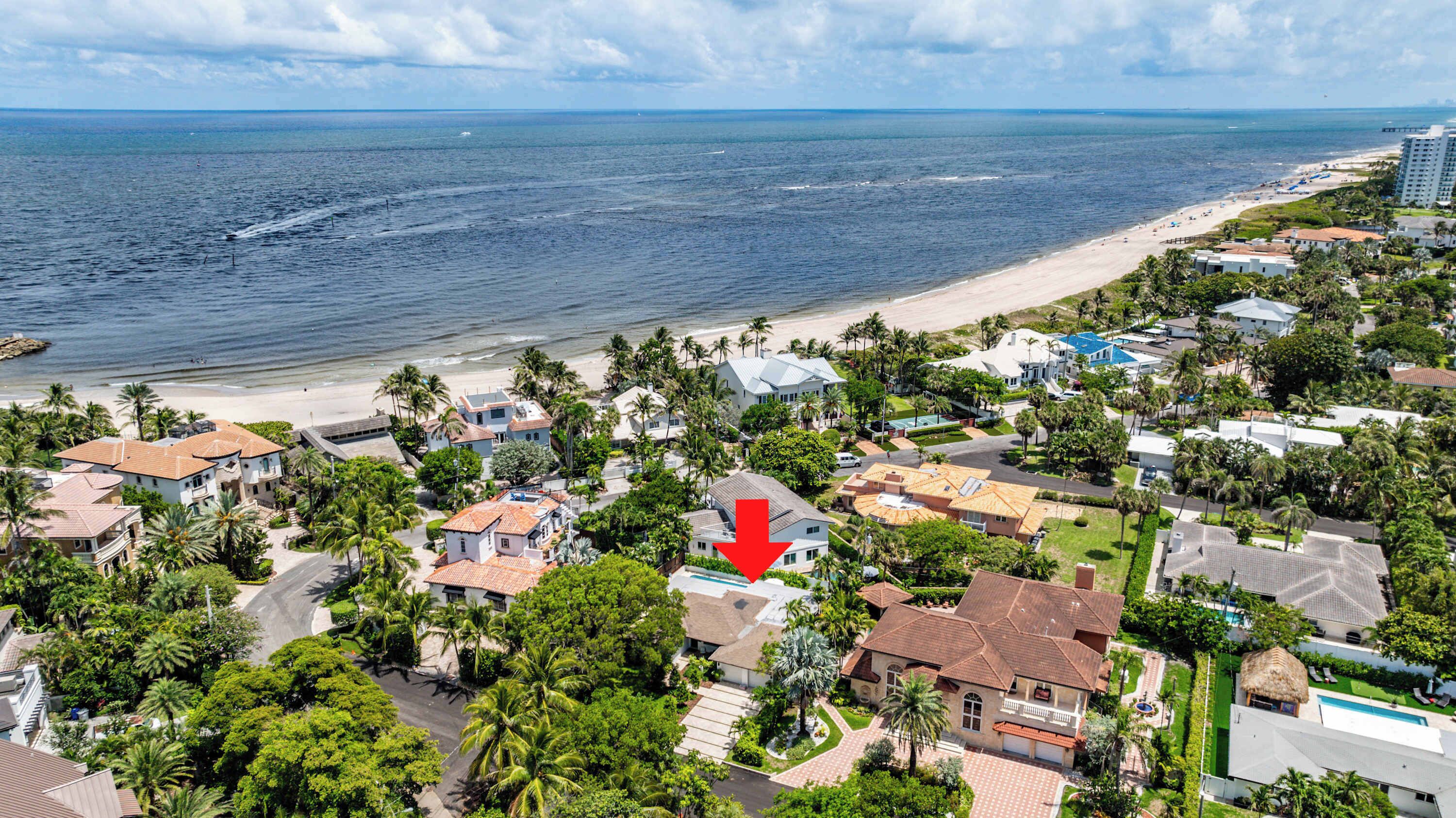 A coastal residential area with houses, a beach, and a large building with a red arrow pointing to it.