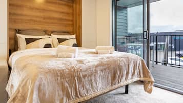 Un dormitorio con una cama grande, cabecera de madera y vistas al balcón exterior.