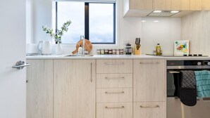 A modern kitchen with light wood cabinets, a stainless steel oven, and a window providing natural light. - Luxurious Studio: Prime location, City Centre (Christchurch)