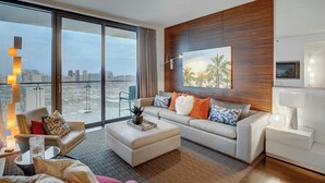 A modern hotel room with a large sliding glass door to a balcony, a sofa set, a flat-screen TV, and a wooden accent wall. - 34th Floor High rise with 180° Strip Views + Open Balcony - No Resort Fees (Las Vegas)
