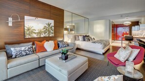 A modern hotel room with a large bed, a sofa, a red armchair, and a dining area. - 34th Floor High rise with 180° Strip Views + Open Balcony - No Resort Fees (Las Vegas)