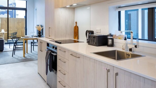 A modern kitchen with light wood cabinets, a stainless steel sink, and a built-in oven. - Single Level Studio, CBD Escape: King bed (Christchurch)