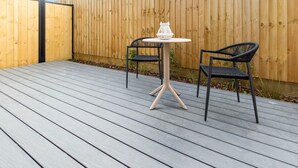 A wooden deck with two black chairs and a white table, surrounded by a wooden fence. - Single Level Studio, CBD Escape: King bed (Christchurch)
