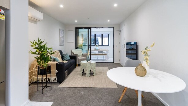 Een moderne woonkamer met een bank, salontafel en een eethoek met tafel en stoelen.