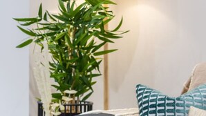 Een moderne woonkamer met een donkergrijze bank, een blauwe vaas op een rond bijzettafeltje en een hoge groene plant.