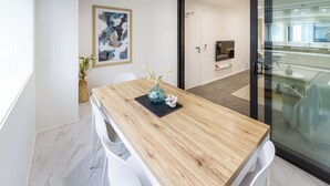 Een moderne kantoorruimte met een houten tafel, witte stoelen, een vaas met bloemen en een schilderij aan de muur.