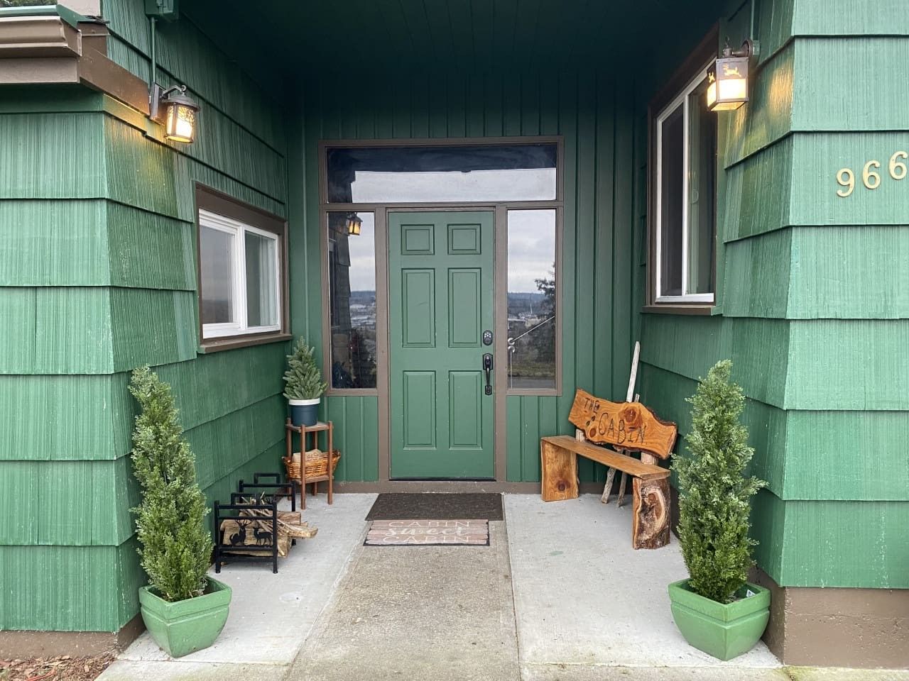 A green building with a green door, a bench, and two potted plants.