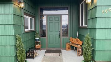 A green building with a green door, a bench, and two potted plants.