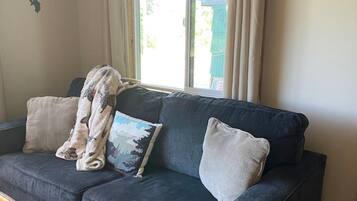 A dark blue sofa with two pillows, a blanket, and a wooden table with a welcome sign.