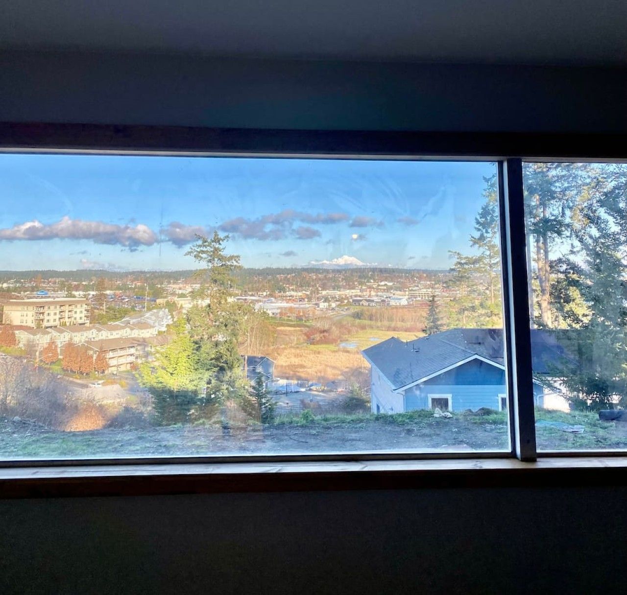 A room with a large window overlooking a residential area with houses and trees.