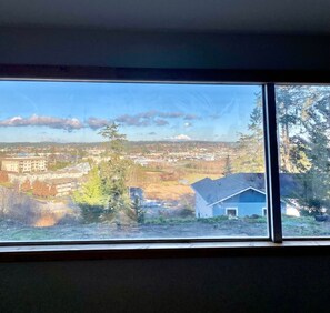 A room with a large window overlooking a residential area with houses and trees. - Cabin * Hot tub * Fire pit * View * Getaway! (Oak Harbor)