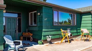 A green house with a number 966, a porch with a bench, and two chairs.