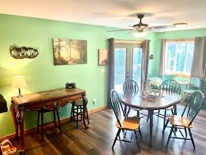A dining area with a round table, chairs, a wooden side table, and a ceiling fan. - Cabin * Hot tub * Fire pit * View * Getaway! (Oak Harbor)