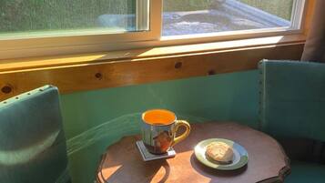 A corner seating area with a table, two chairs, a mug, and a plate with a biscuit.