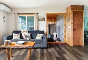 A living room with a sofa, coffee table, and a wooden door. - Cabin * Hot tub * Fire pit * View * Getaway! (Oak Harbor)