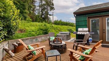 Une terrasse extérieure avec des chaises en bois, une table, un barbecue et un foyer.