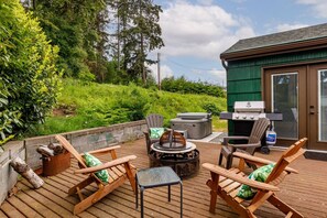 An outdoor deck with wooden chairs, a table, a grill, and a fire pit. - Cabin * Hot tub * Fire pit * View * Getaway! (Oak Harbor)