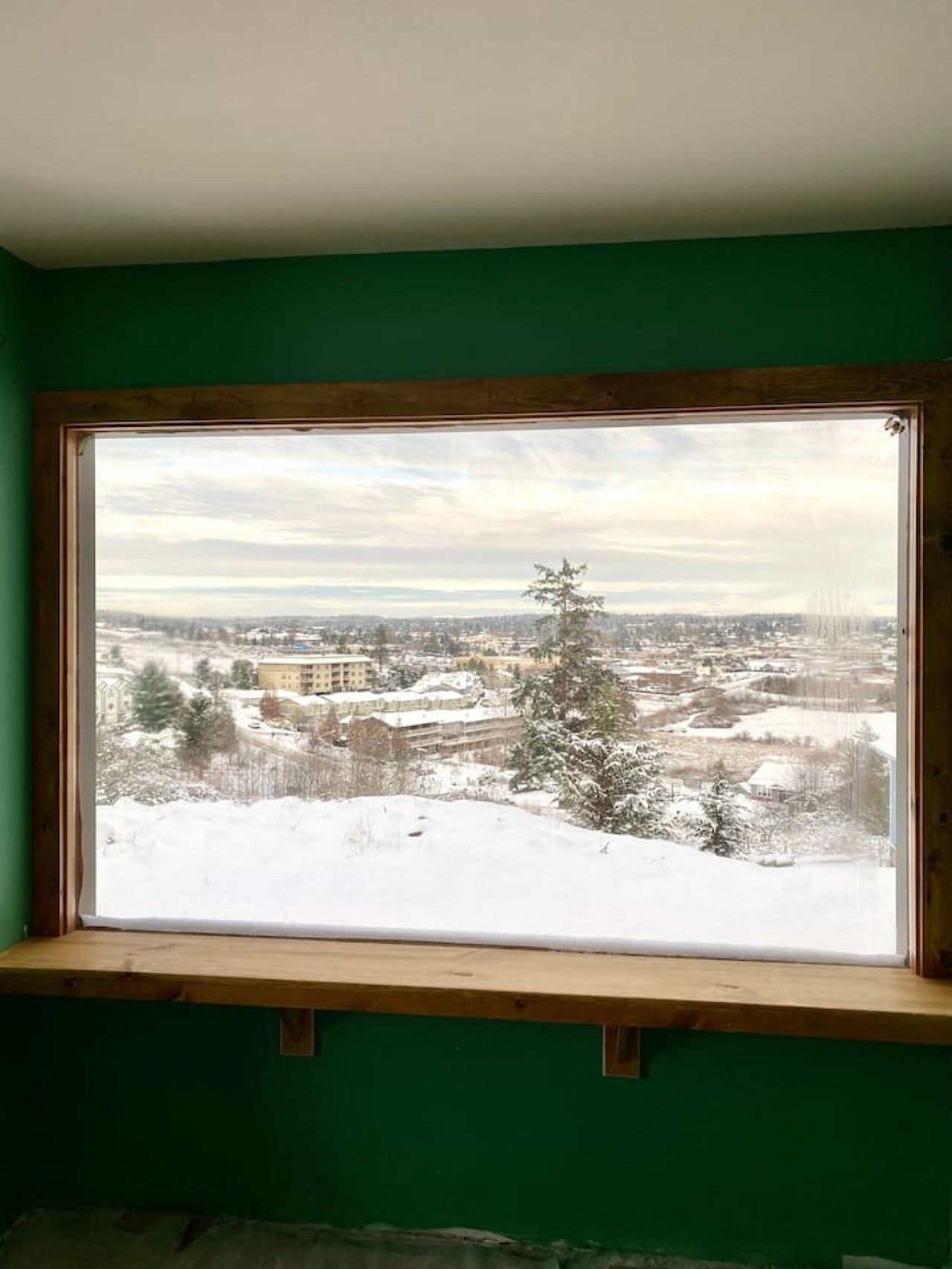 Une pièce dotée d’une grande fenêtre donnant sur un paysage enneigé et sur une ville lointaine.