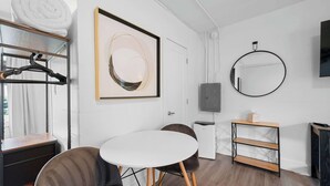 A modern room with a round table, two chairs, a white sofa, a framed abstract artwork, a round mirror, a TV, and a small cabinet. - Chic City Retreat 93B (Columbus)