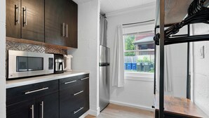A modern kitchen with dark cabinets, a stainless steel refrigerator, a microwave, and a coffee maker. - Chic City Retreat 93B (Columbus)