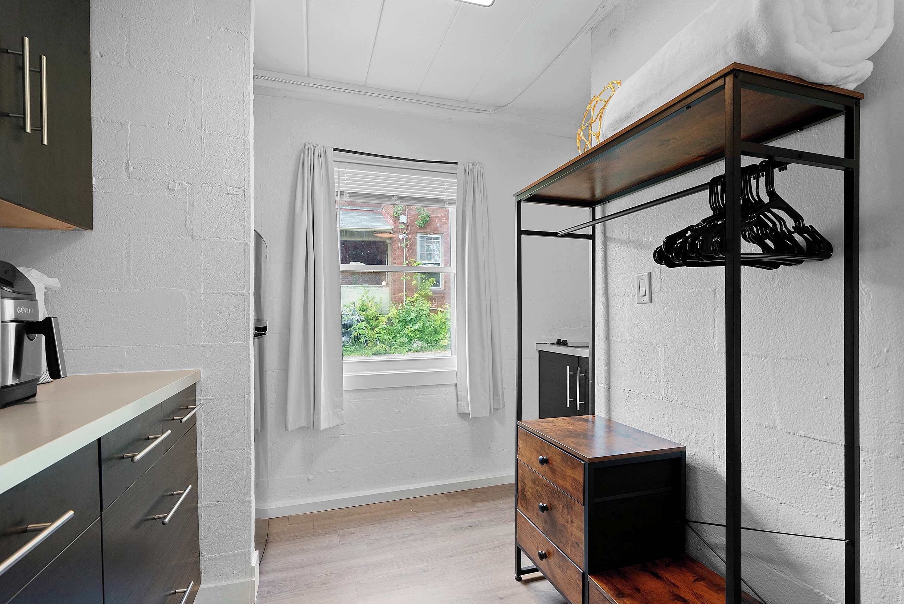 A modern kitchen with a built-in oven, a wooden cabinet, and a window with curtains.