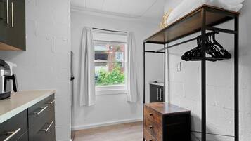 A modern kitchen with a built-in oven, a wooden cabinet, and a window with curtains.