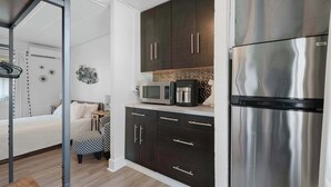 A compact kitchen with dark cabinets, a stainless steel refrigerator, a microwave, and a coffee maker. - Chic City Retreat 93B (Columbus)