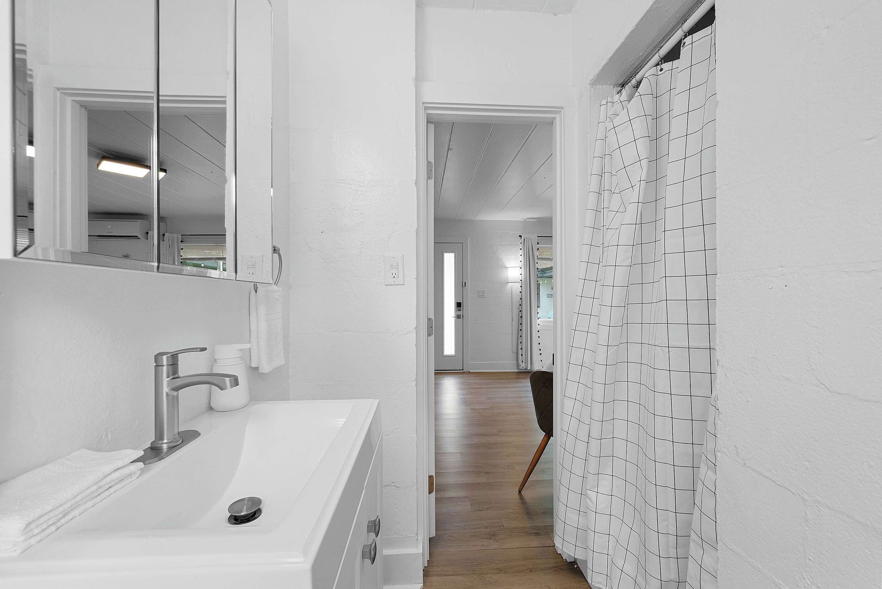 Un baño con lavamanos blanco, espejo y cortina de ducha.