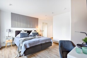 Una camera da letto moderna con un letto, comodini, una sedia e un quadro di grandi dimensioni appeso al muro.
