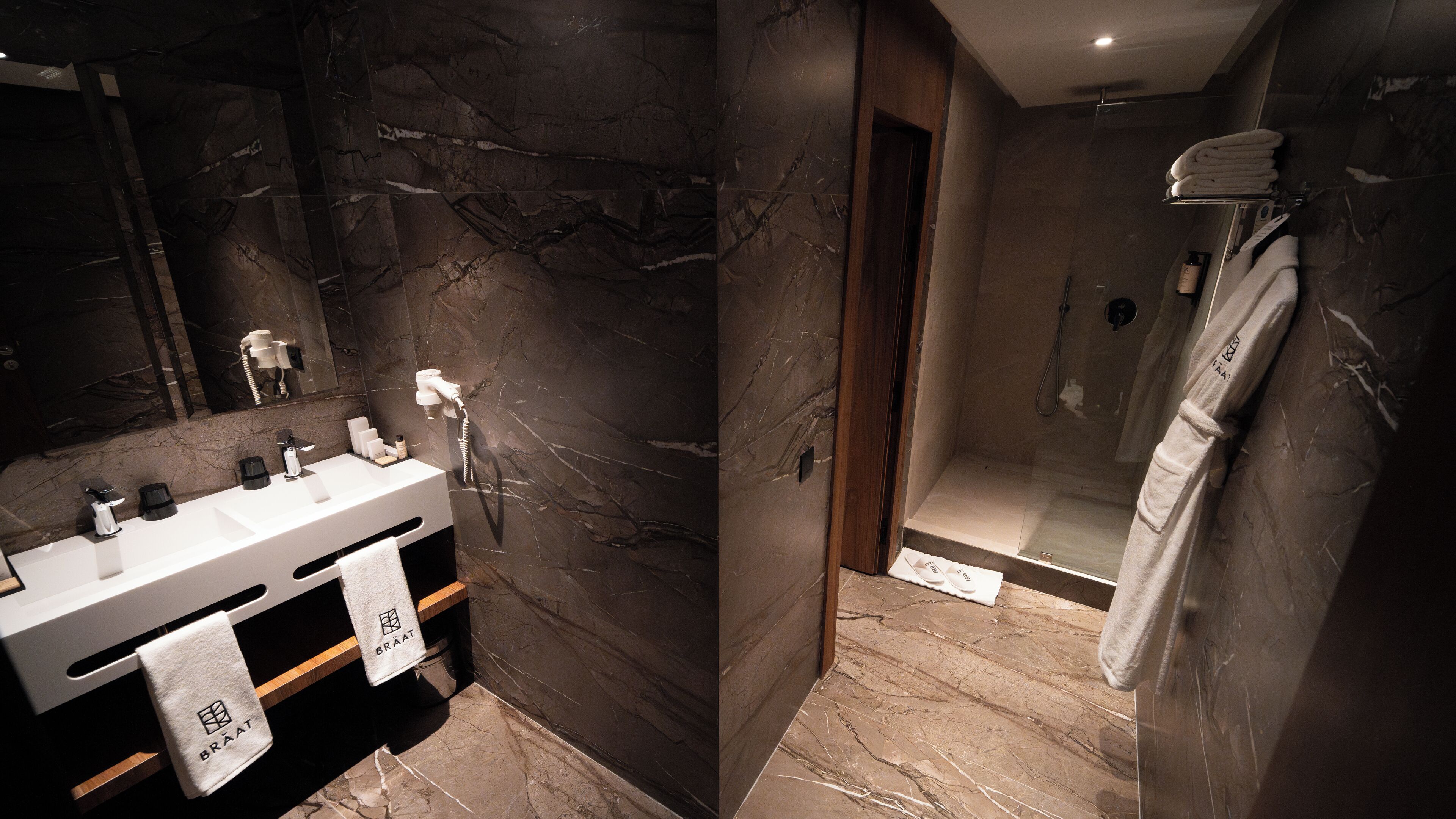 Un baño moderno con encimera de mármol, ducha y toallero.