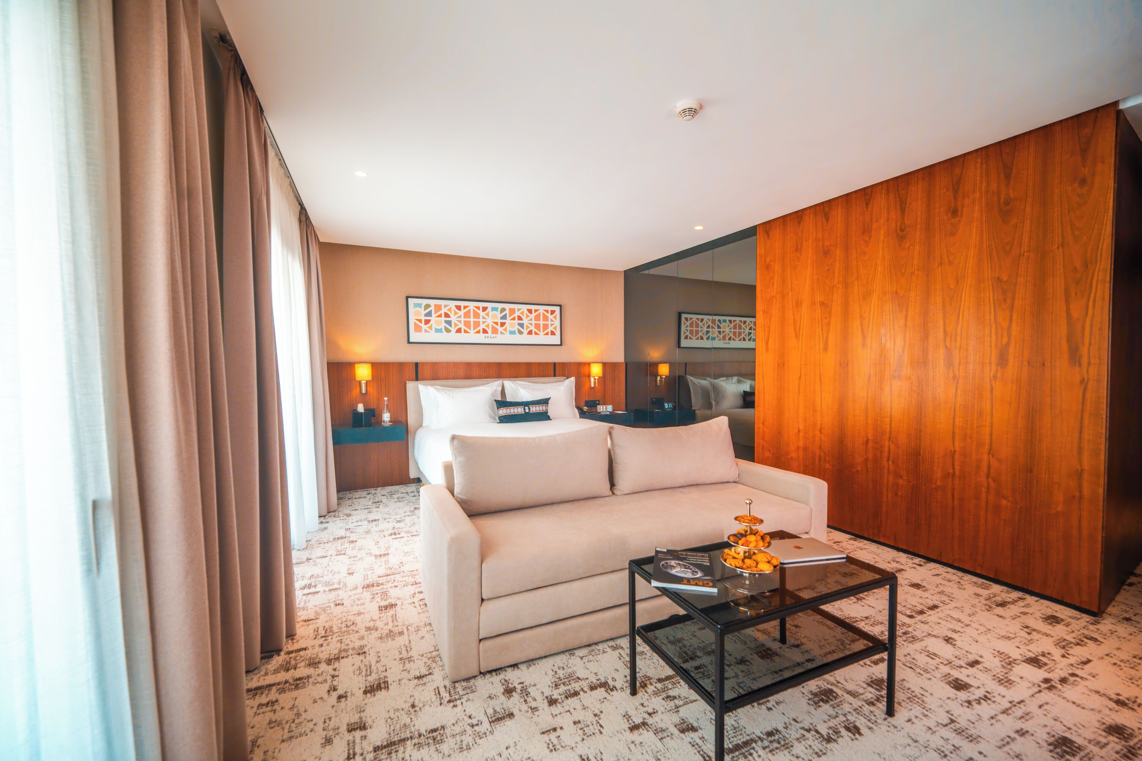 Una habitación de hotel moderna con un sofá, una mesita de centro y un espejo grande.