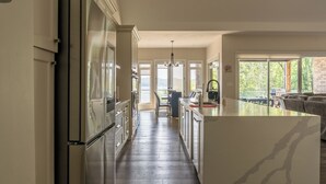 A modern kitchen with a central island, built-in appliances, and a view to an outdoor patio area.