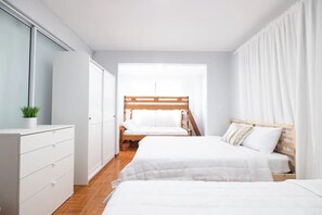 Un dormitorio con dos camas, un aparador y una ventana con cortinas.