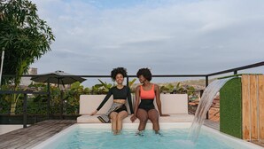 Two people sitting by a pool with a waterfall feature. - Casa Helena Hostel Cartagena (Cartagena)
